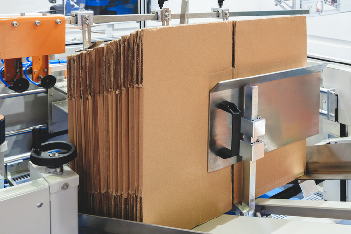 A pile of corrugated boxes are in a production line